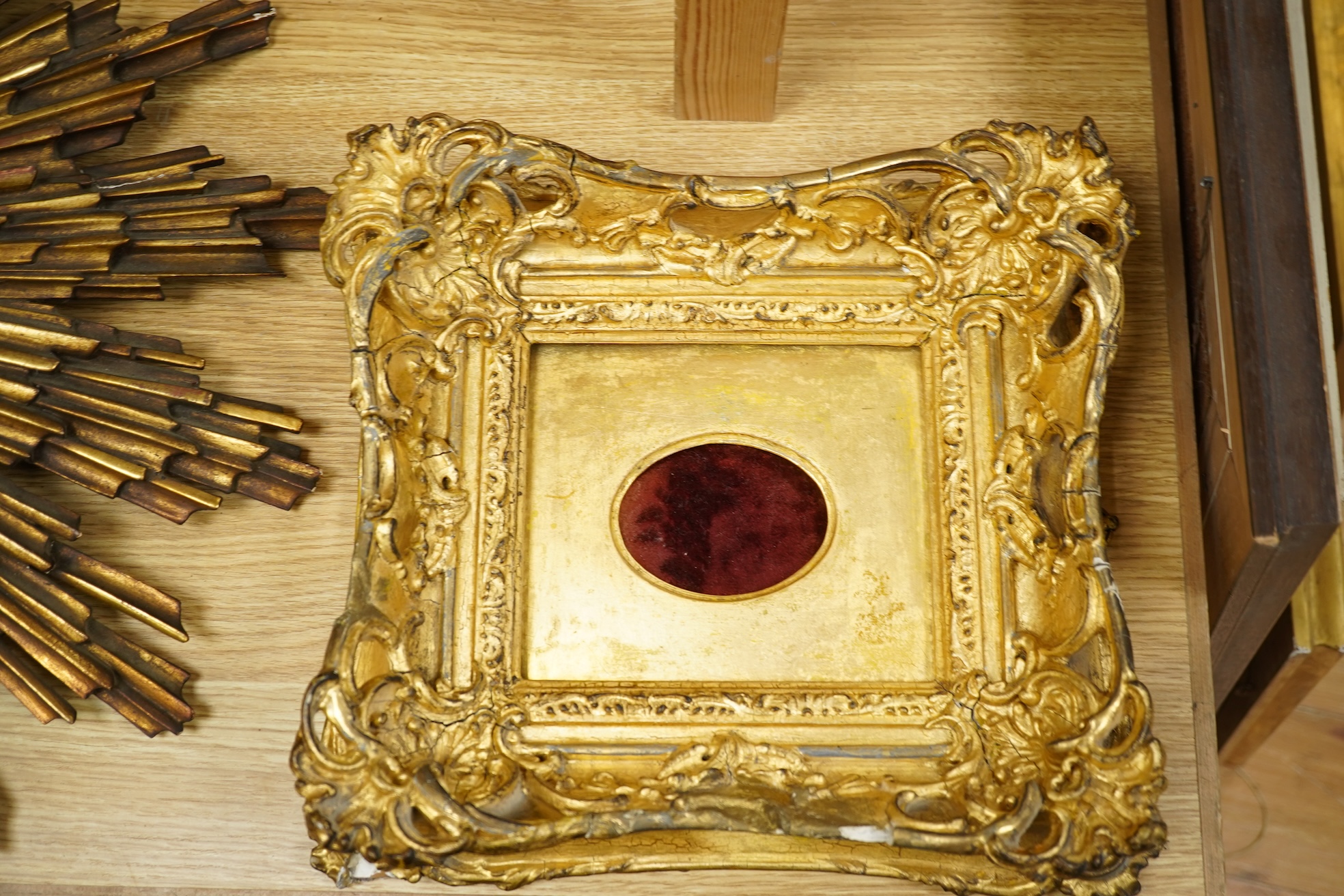 A gilt decorated sun burst clock frame, 63cm wide and a mid 19th century ornate gilt miniature frame